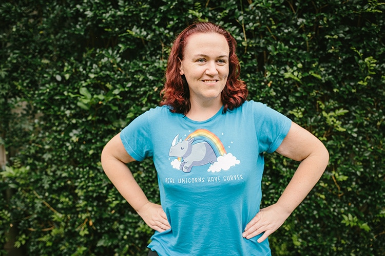 Suzanne wearing a blue t-shirt with a rhino jumping through a rainbow and the text "real unicorns have curves"
